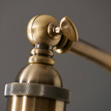 Close-up of the Endon Bramdale floor lamp's antique brass adjustable head joint, showing the ball pivot, knurled shade collar, and angled arm.