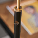 Close-up of the Endon Bramdale floor lamp's adjustable stem, showing knurled brass tightening knobs on the matt black tubular column.