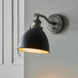 Endon Bramdale industrial wall light with adjustable matt black dome shade and aged pewter bracket, mounted beside a white panelled door.