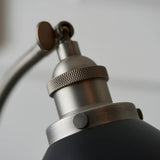 Close-up of the Endon Bramdale table lamp's adjustable knuckle joint, showing brushed silver metalwork, knurled ring detail and matt black shade edge.