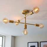 Endon Marlowe 5 Light Semi-Flush Ceiling Light in satin brass, with five angled arms holding exposed globe bulbs, mounted on a white ceiling.