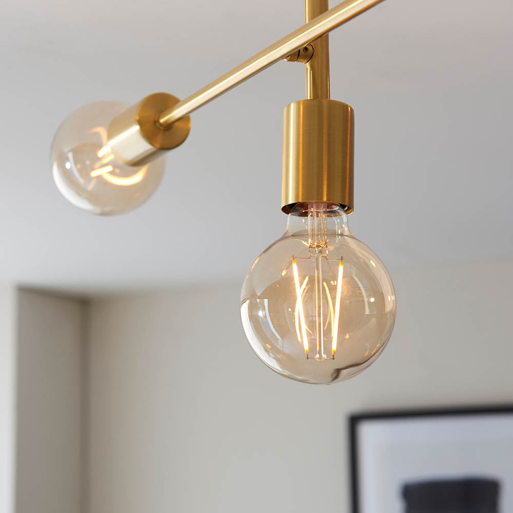 Endon Marlowe satin brass semi-flush ceiling light shown close-up, with two exposed E27 globe bulbs on slim brass arms against a pale ceiling.