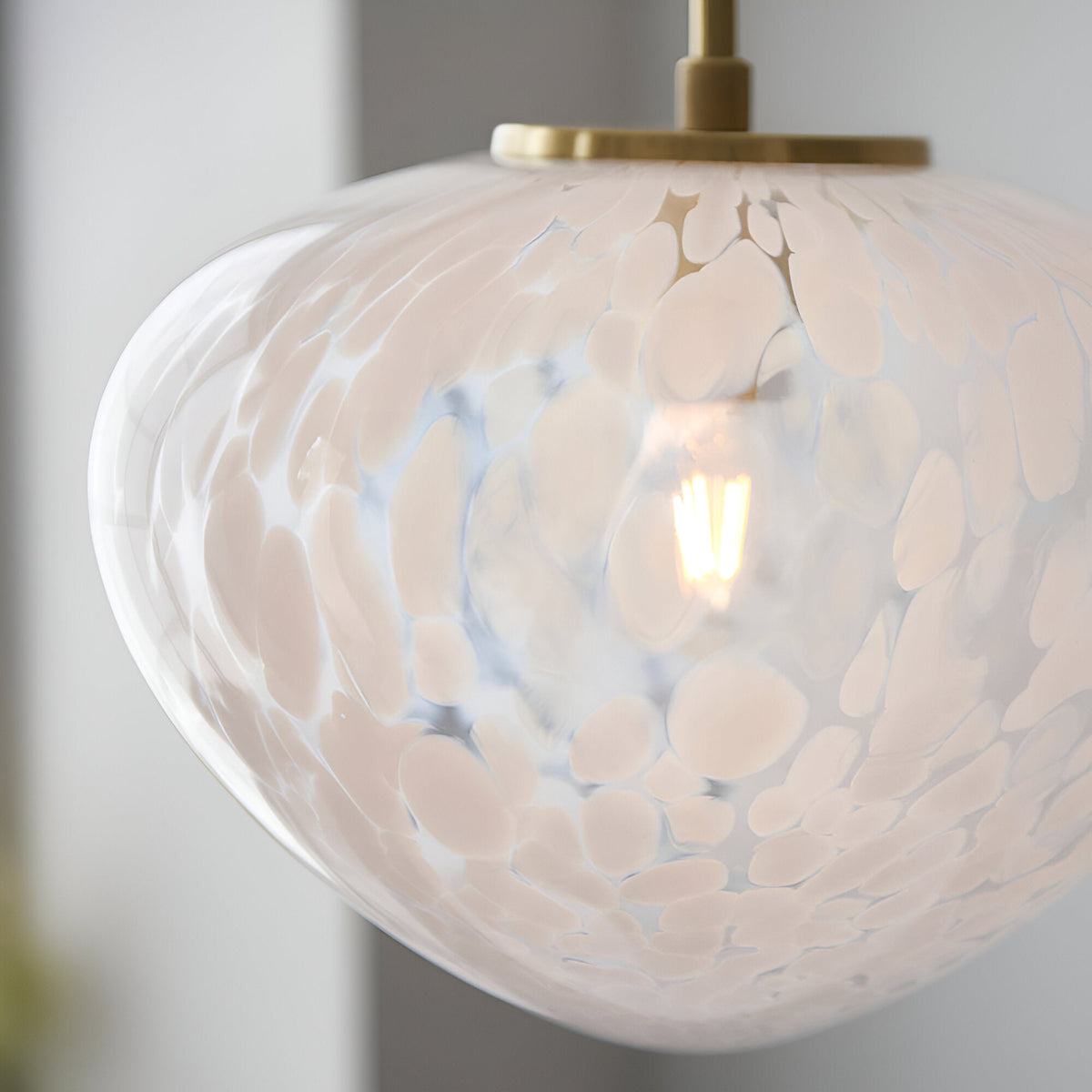 Close-up of the Calloway Pendant light, a dome-shaped white confetti glass shade on satin brass fitting with visible E27 bulb inside.
