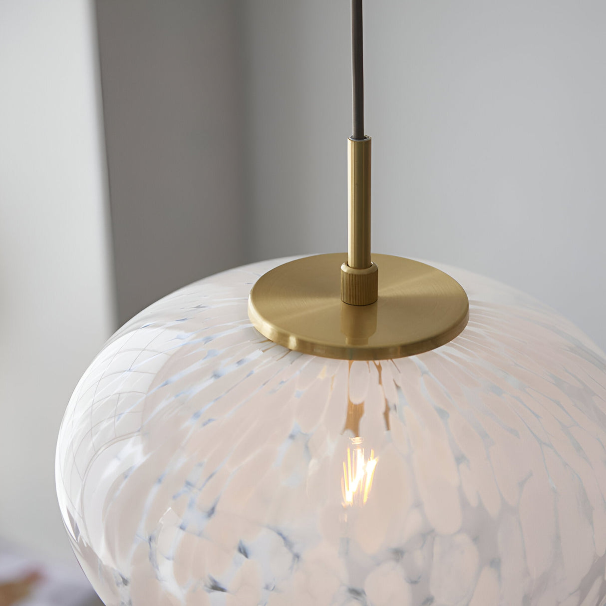Close-up of the Calloway Pendant in brass and white, showing a speckled confetti glass shade beneath a satin brass ceiling rose and rod.