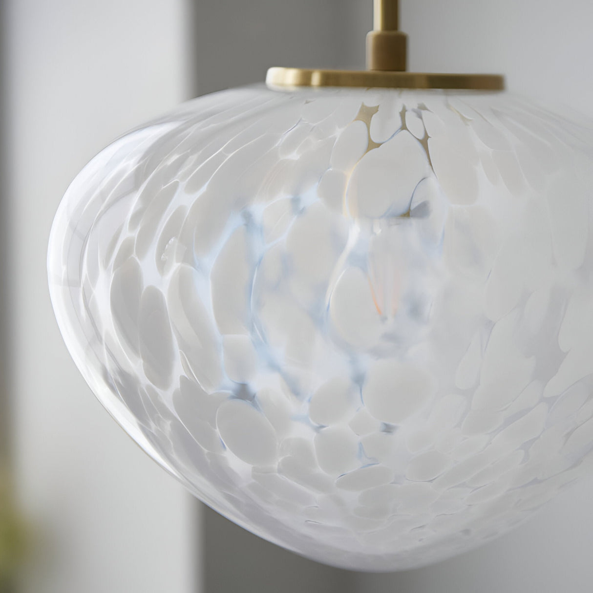 Close-up of the Calloway Pendant in brass and white, showing a rounded glass shade with a speckled confetti effect and satin brass ceiling mount.