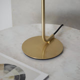 Close-up of the Endon Calloway table lamp's satin brass circular base and slim upright stem on a marble surface, with black fabric flex.