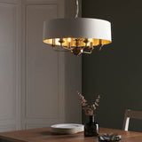 Endon Brenley V1 six-light pendant with white drum shade, gold-lined interior and antique brass multi-arm frame, suspended above a dining table.