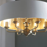 Close-up of Endon Brenley V1 6 light pendant showing antique brass arms holding six E14 lamps beneath a white fabric shade with gold-lined interior.