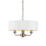 Endon Brenley 3 light pendant in antique brass with a vintage white drum shade and gold-lined interior, suspended on a chain against a white background.