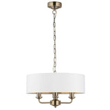 Endon Brenley 3 Light Pendant in antique brass with a white drum shade and gold-lined interior, suspended on a brass chain against a white background.