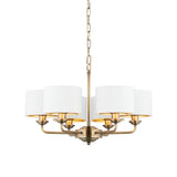 Brenley V2 six-light pendant with antique brass metalwork, six white fabric drum shades, and a chain suspension, shown on a plain white background.