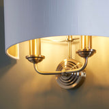 Close-up of Endon Brenley 2 Light Wall Light in antique brass with twin upward E14 lamp holders, circular backplate and white linen shade with gold inner.