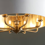Close-up of Endon Brenley 8 light pendant showing antique brass arms, candle lamps and gold-lined vintage white fabric shade interior.