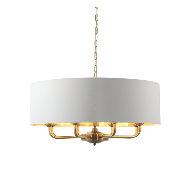 Endon Brenley pendant light with antique brass multi-arm frame and white drum shade with gold-lined interior, suspended from a chain on a white background.