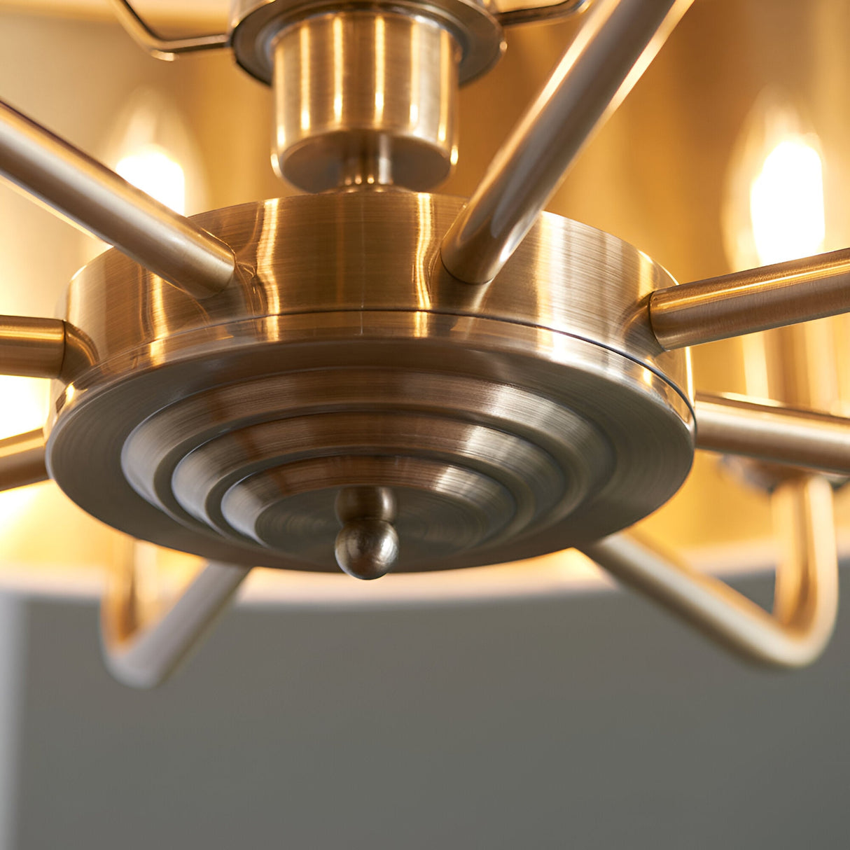 Close-up of the Endon Brenley 8 light pendant showing the antique brass central hub with ridged detailing and multi-arm spokes extending to lit shades.