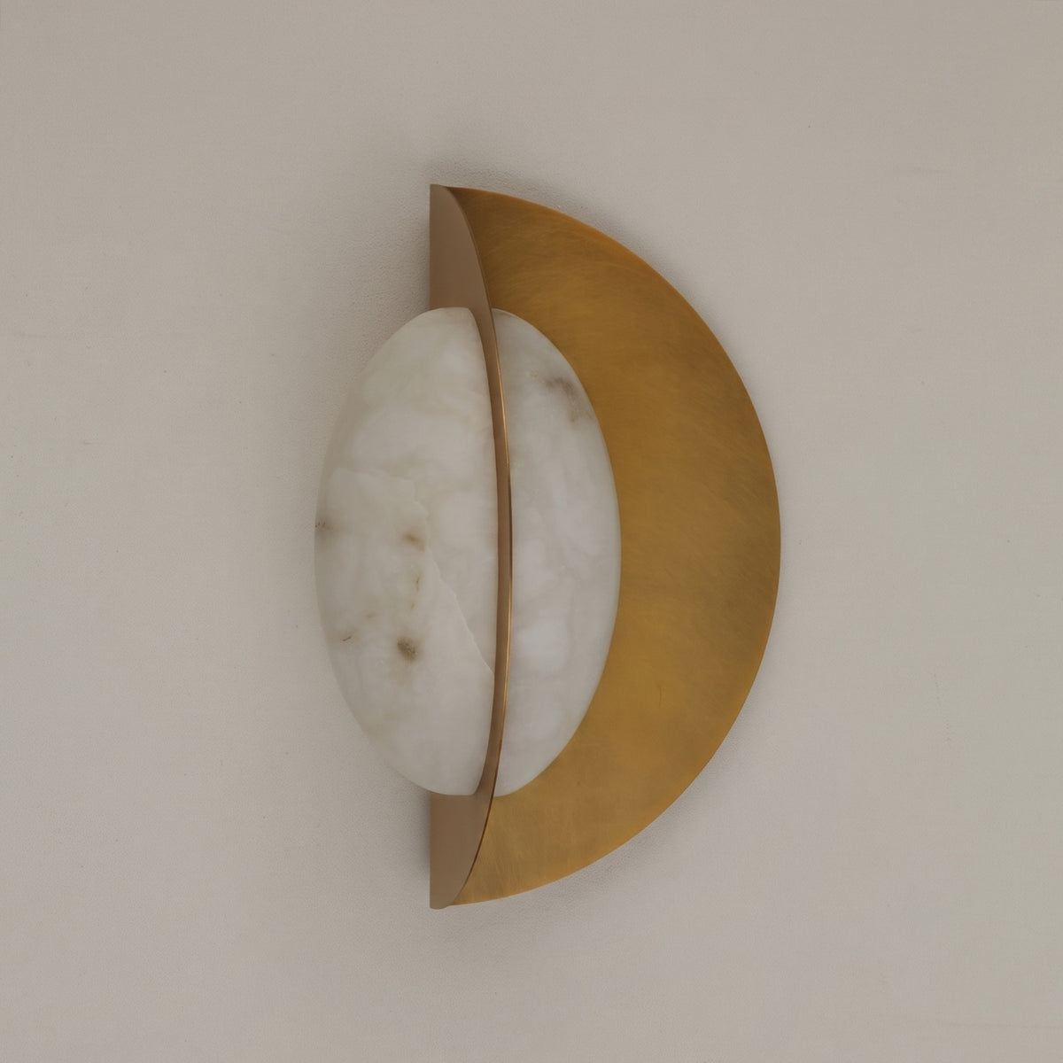 Althia LED Alabaster Wall Light in brushed brass, with a rounded natural alabaster diffuser set against a half-moon brass backplate, shown on a plain light background.