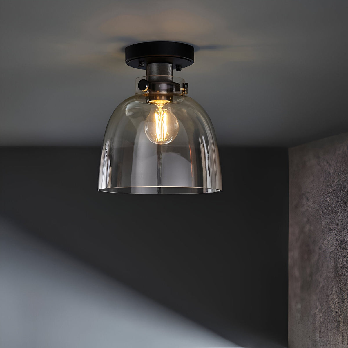 Endon Camden flush ceiling light in matt black with a domed clear glass shade and single E27 filament bulb, mounted on a grey ceiling.