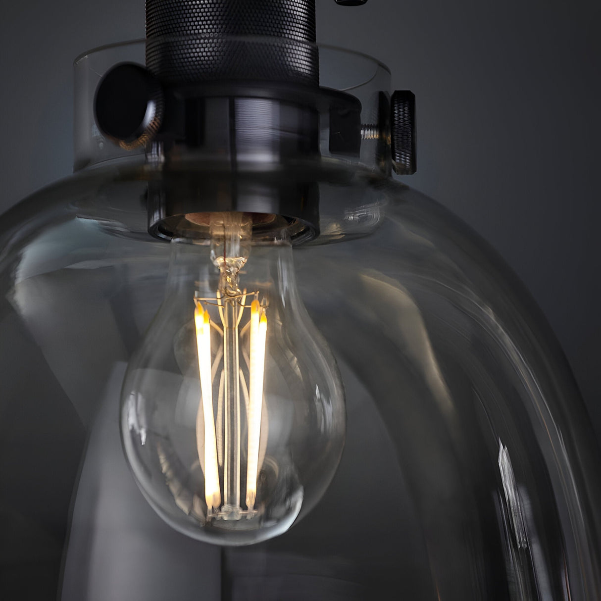 Close-up of Endon Camden matt black flush ceiling light showing the illuminated E27 filament bulb behind a clear glass shade with knurled metal fittings.