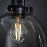Close-up of Endon Camden matt black flush ceiling light showing the illuminated E27 filament bulb behind a clear glass shade with knurled metal fittings.