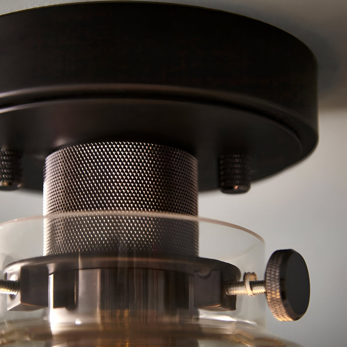 Close-up of the Endon Camden matt black flush ceiling light showing knurled thumbscrews, mesh bulb cage detail and clear glass shade rim.
