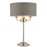 Endon Brenley 3 light table lamp with grey linen drum shade, nickel three-arm fitting and slim stem on a round base, shown on a white background.