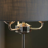 Close-up of Endon Brenley 3 Light Table Lamp showing polished nickel three-arm centre fitting beneath a grey linen-mix drum shade.