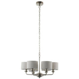 Brenley 6-light pendant in brushed chrome with six curved arms and grey linen drum shades, hung from a long chain on a plain white background.