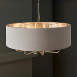 Endon Brenley 8 light pendant in brushed chrome with a large natural linen drum shade, metallic inner and multi-arm frame, suspended on a chain.
