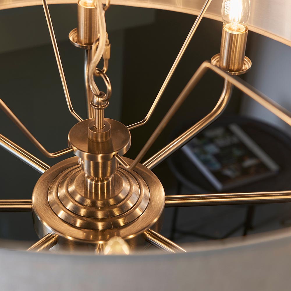 Close-up of the Endon Brenley 8 Light Pendant showing the antique brass central hub, ridged detailing, chain suspension and radiating arms with lit E14 lamps.