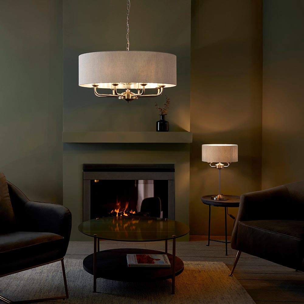 Endon Brenley pendant light with natural linen drum shade and chrome multi-arm fitting, above a fireplace in a green-walled living room.