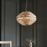 Endon Aldton 5 light crystal pendant in polished nickel with faceted crystals on a chain, hanging above a dining table against dark panelled walls.