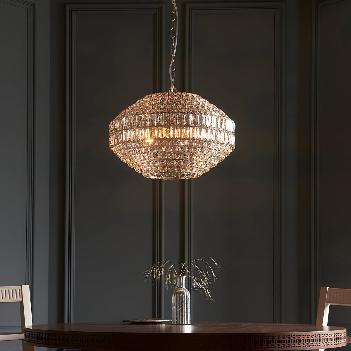 Endon Aldton 5 light crystal pendant in polished nickel with faceted crystal cluster, hung from a chain above a dining table against dark panelled walls.