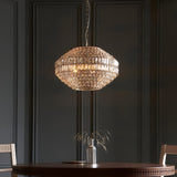 Endon Aldton 5 light crystal pendant in polished nickel with faceted crystal cluster, hung from a chain above a dining table against dark panelled walls.