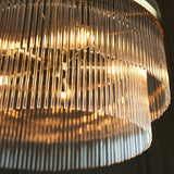 Close-up of the Endon Beaumont 5 Light Pendant in brass, showing tiered clear glass rods around illuminated E14 lamps.
