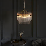 Endon Beaumont 3 Light Pendant in brass with two tiers of clear glass rods, illuminated above a small side table in a dark panelled room.