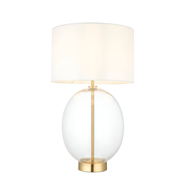 Brockmere Table Lamp with an oversized oval clear glass base, satin brass stem and base plate, and a white fabric drum shade on a plain background.