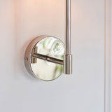 Close-up of the Endon Cliffhurst wall light in polished nickel, showing the round wall plate, slim upright and cylindrical fitting against a white wall.