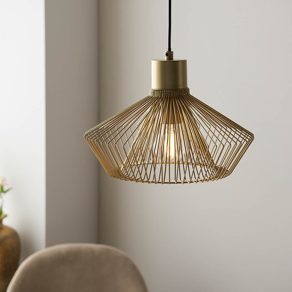Endon Brockton cage pendant light in polished gold, with an open wire shade around an exposed filament bulb on a black flex, in a dining setting.