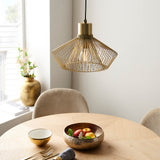Endon Brockton cage pendant light in polished gold, hanging over a round wooden dining table set with a fruit bowl and beige velvet chairs.