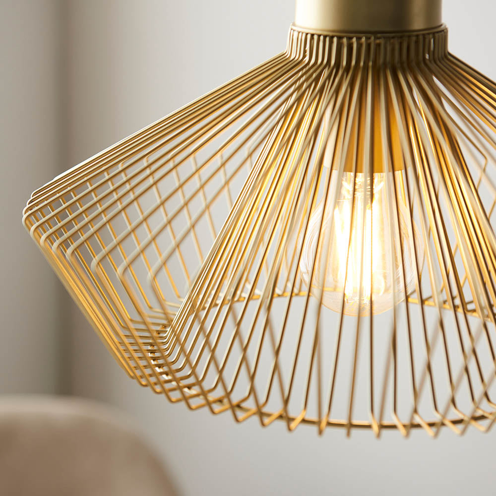 Endon Brockton cage pendant light in polished gold, wide flared metal wire shade with visible E27 filament bulb, shown lit in a softly blurred interior.
