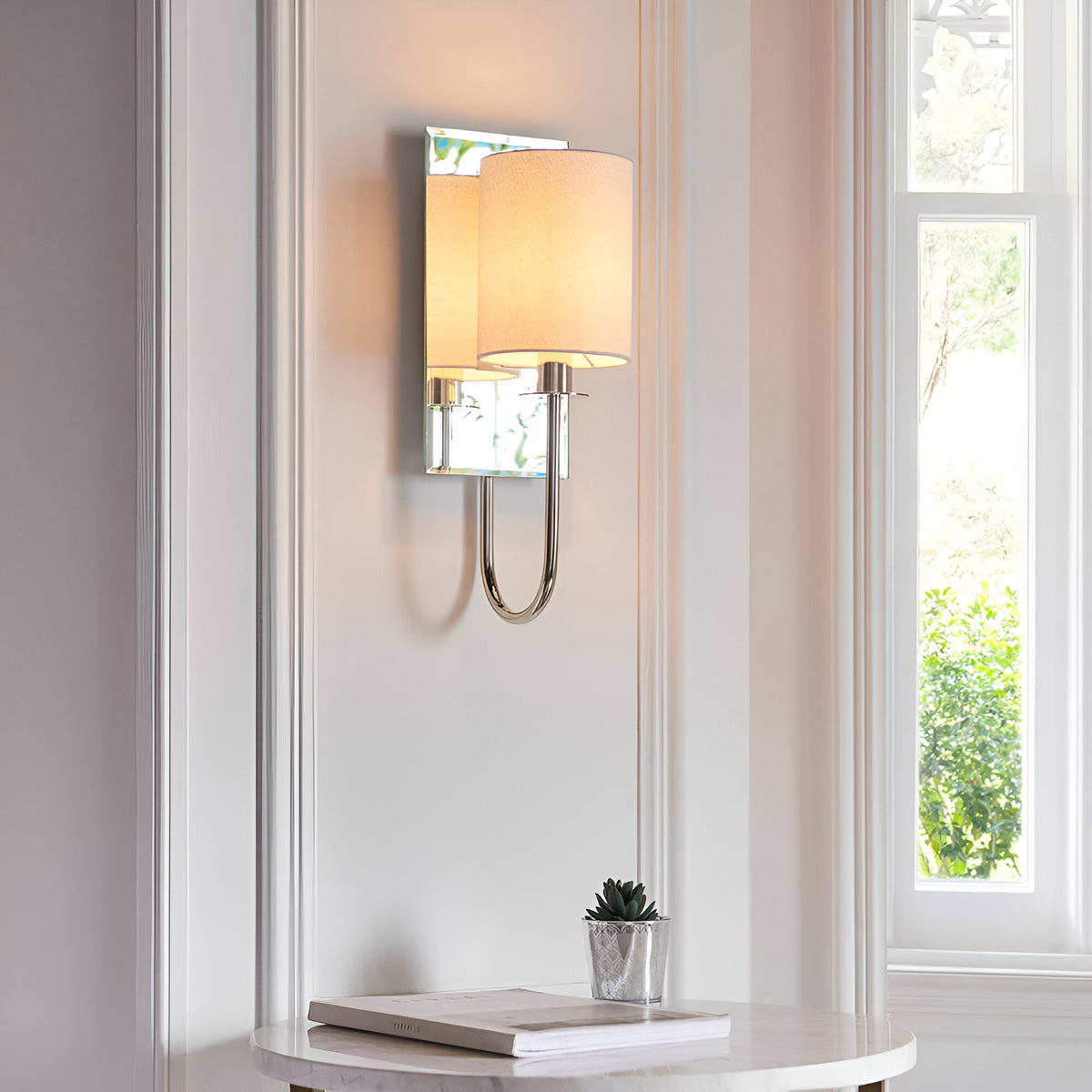 Endon Carlhurst wall light with bevelled mirrored back plate, polished nickel arm and vintage white fabric shade, mounted in a bright hallway alcove.