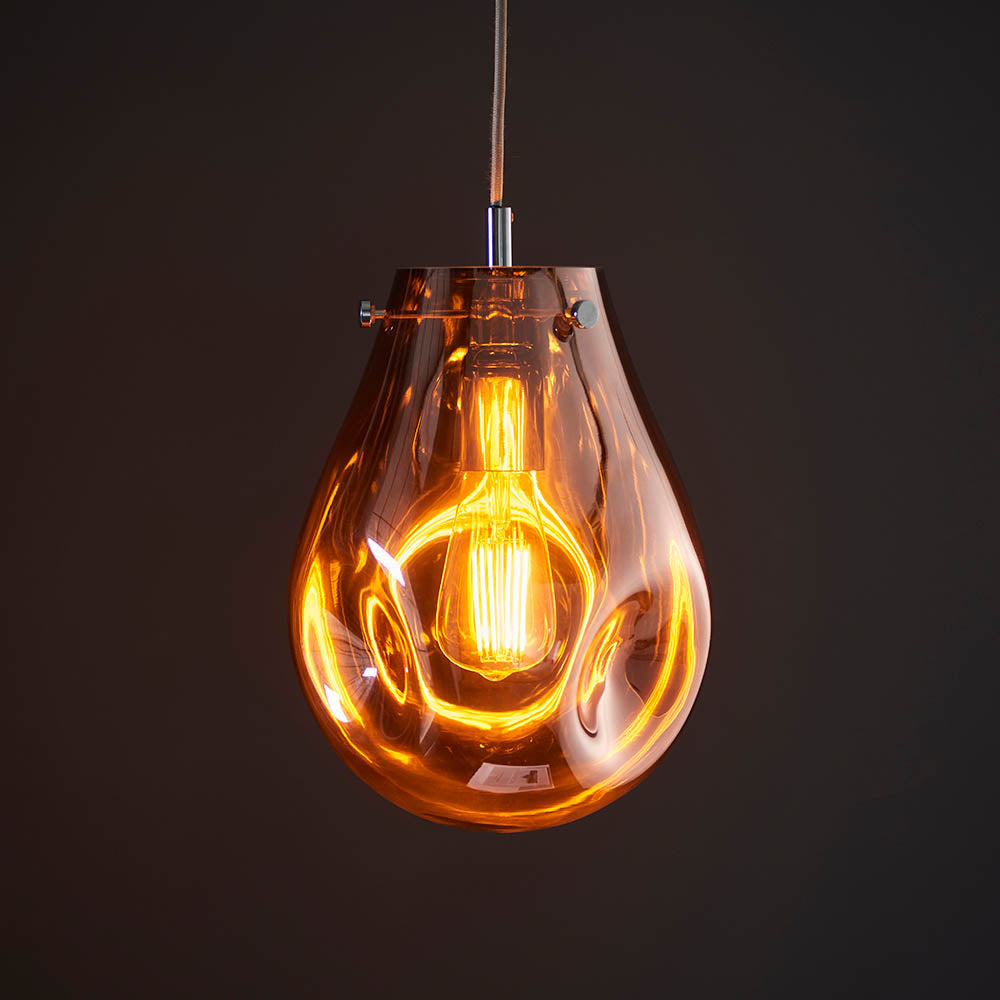 Brackwell Glass Pendant in Copper, a teardrop-shaped pendant light with molten copper glass shade and chrome fittings, shown lit against a dark background.