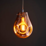 Brackwell Glass Pendant in Copper, a teardrop-shaped pendant light with molten copper glass shade and chrome fittings, shown lit against a dark background.