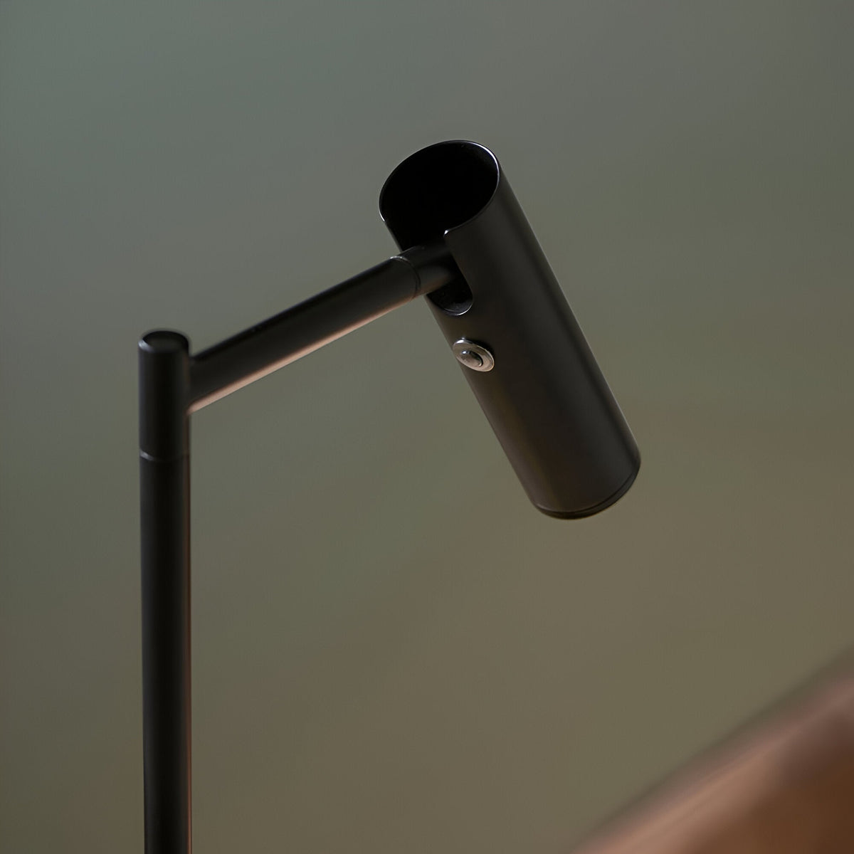 Close-up of the Endon Brackbourne floor lamp's adjustable cylindrical head in matt black, with push button switch on the tilting arm.