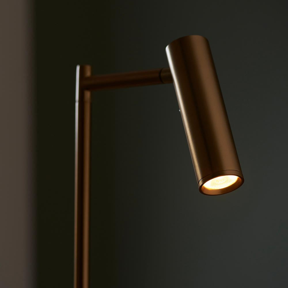 Endon Brackbourne floor lamp in warm brass, close-up of the adjustable cylindrical head lit with warm white LED against a dark background.