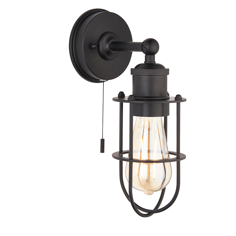 Black industrial-style Bevwood bathroom wall light with open cage design, round wall plate, pull cord switch and exposed E27 filament bulb.