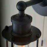 Close-up of the Bevwood industrial wall light in matte black metal, showing the knurled cage detail and pull-cord fitting against a neutral background.