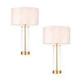 Endon Caldley twin pack table lamps with clear cylindrical glass bases, satin brass fittings and vintage white drum shades, shown on a plain background.