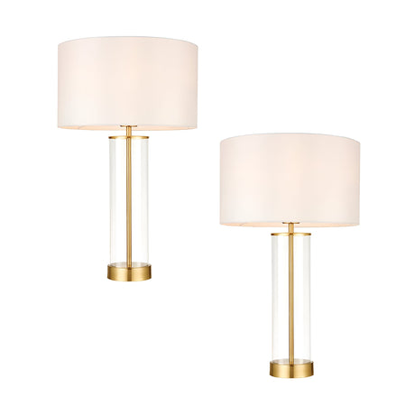 Endon Caldley twin pack table lamps with clear cylindrical glass bases, satin brass fittings and vintage white drum shades, shown on a plain background.