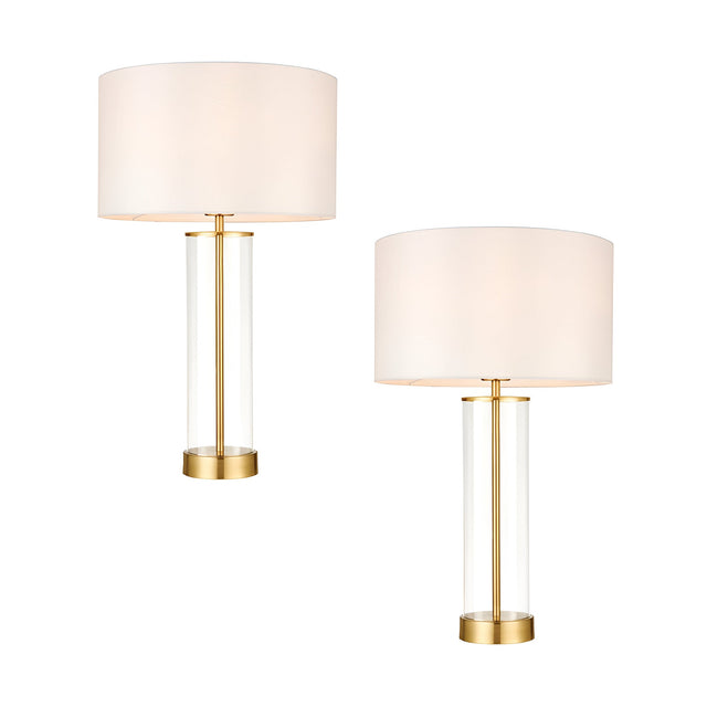 Endon Caldley twin pack table lamps with clear cylindrical glass bases, satin brass fittings and vintage white drum shades, shown on a plain background.